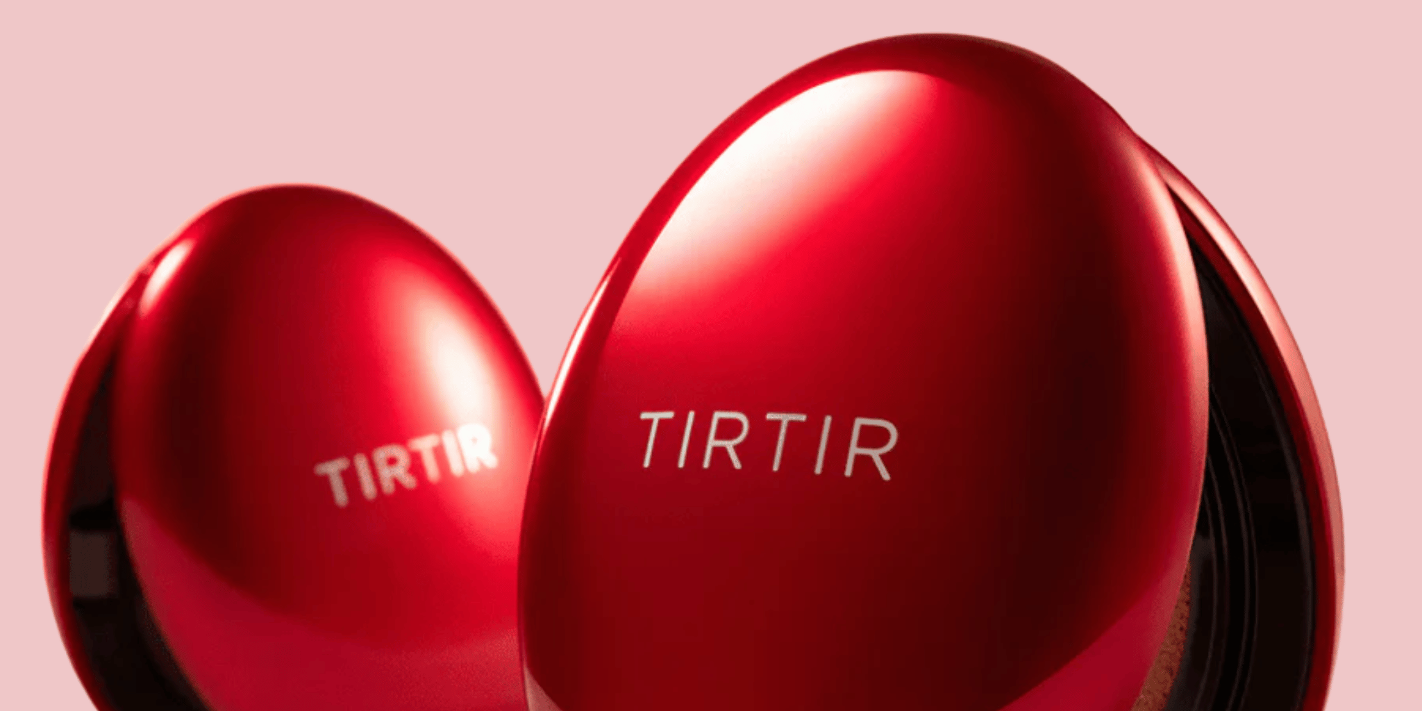 Bilden visar två röda, blanka foundation från märket TIRTIR mot en rosa bakgrund.