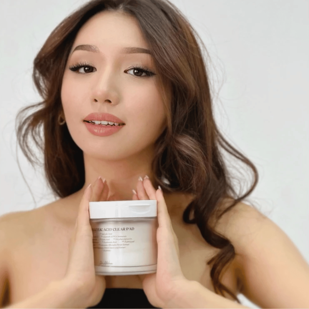 Model drži Dr. Althea 2% Salicylic Acid Clear Pad pred obrazom. Eksfoliacijske tonik blazinice s salicilno kislino, ki čistijo pore, uravnavajo sebum in zagotavljajo jasnejšo kožo.