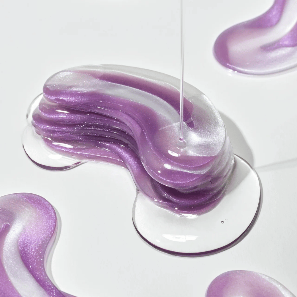 Vijolična hidrogelna tekstura iz 360° Shot PDRN Glowing Eye Patch s sijočimi plastmi, ki prikazujejo vlažilno in sijajno konsistenco za področje oči.