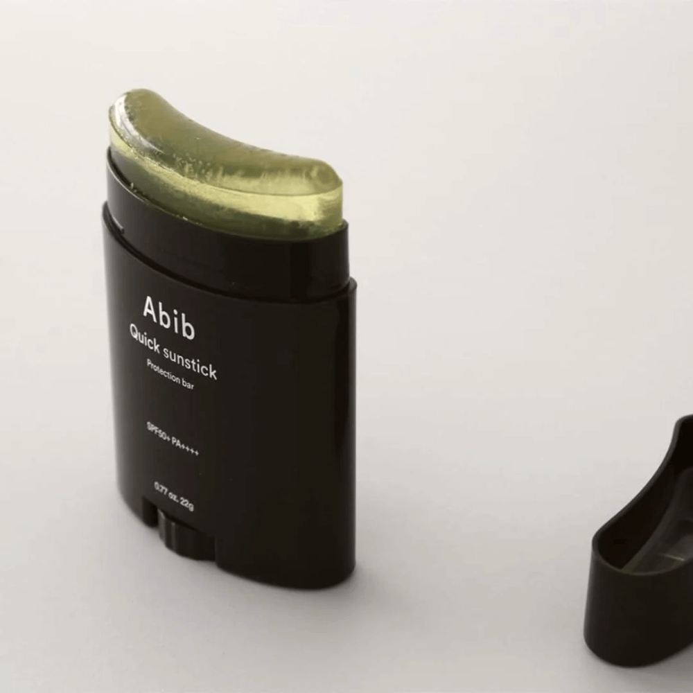 Črna cev z zelenim pokrovčkom, ki vsebuje Quick Sunstick Protection Bar SPF50+ PA++++ 22g od Abib za zaščito pred soncem.