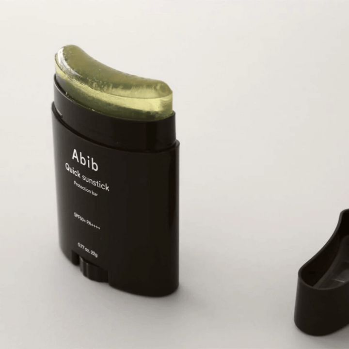 Črna cev z zelenim pokrovčkom, ki vsebuje Quick Sunstick Protection Bar SPF50+ PA++++ 22g od Abib za zaščito pred soncem.