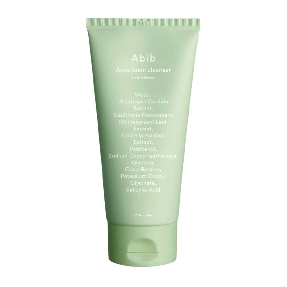 Zelena tuba z Abib Acne Foam Cleanser Heartleaf Foam, ki prikazuje sestavine, kot so Houttuynia Cordata, Centella Asiatica in salicilna kislina, natisnjene na sprednji strani. Izdelek stoji pokonci na beli podlagi.