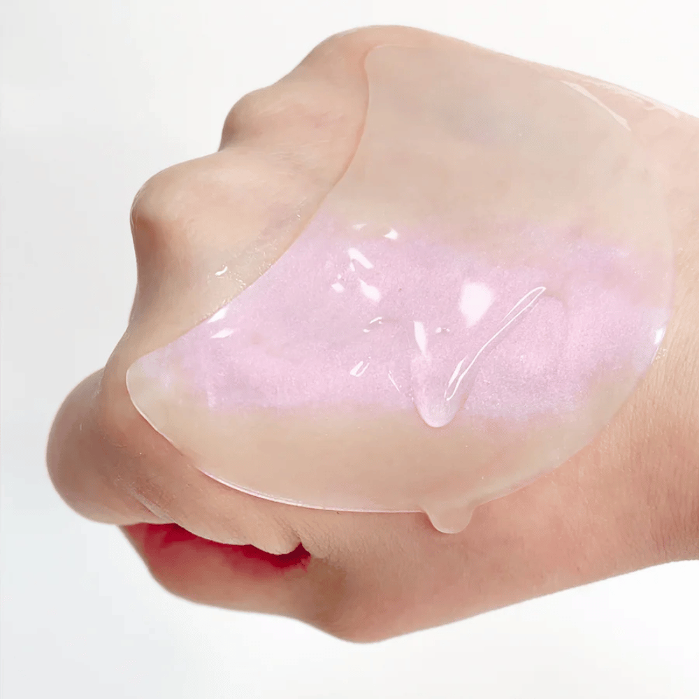 Rosa hydrogel eye patch med retinol visas på en hand, återfuktande och lystergivande formula.