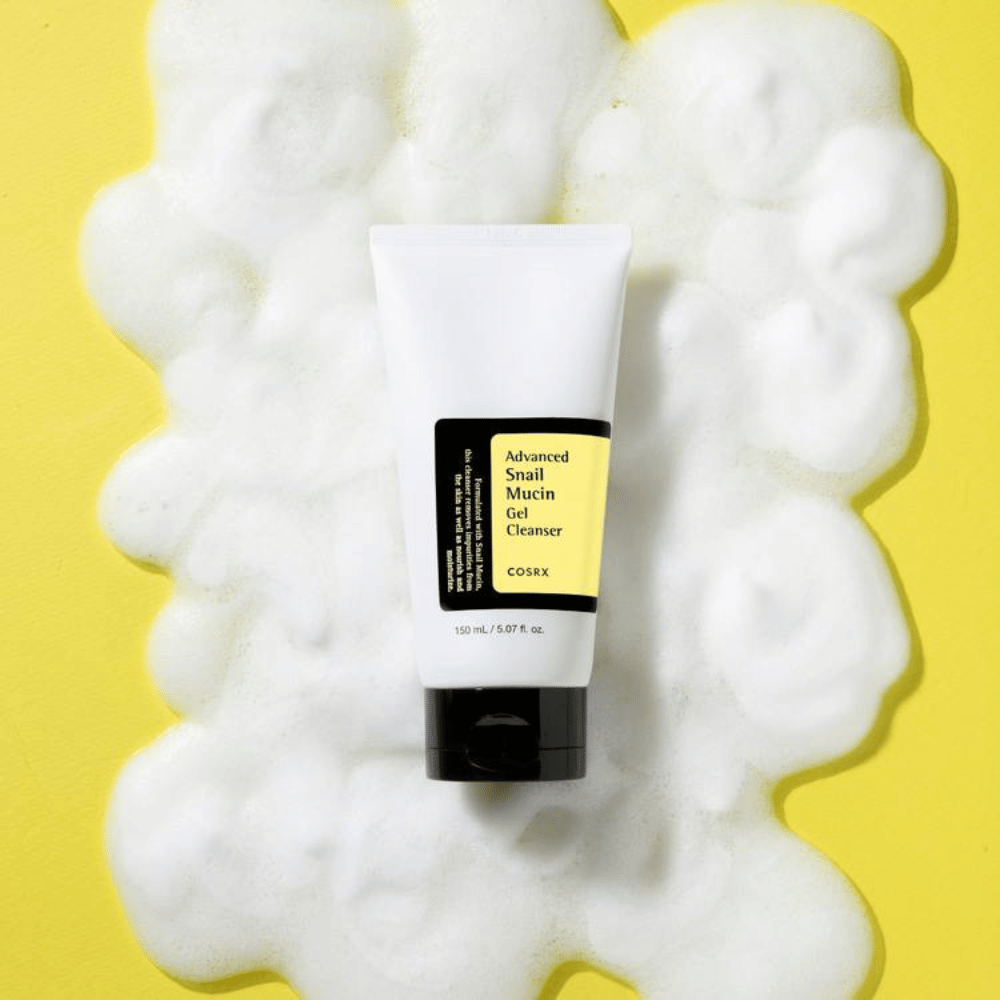 COSRX Advanced Snail Mucin Gel Cleanser 150 ml obkrožen z bogato peno na rumenem ozadju – nežno korejsko čistilo za obraz z snail mucin za vlaženje in sijaj.