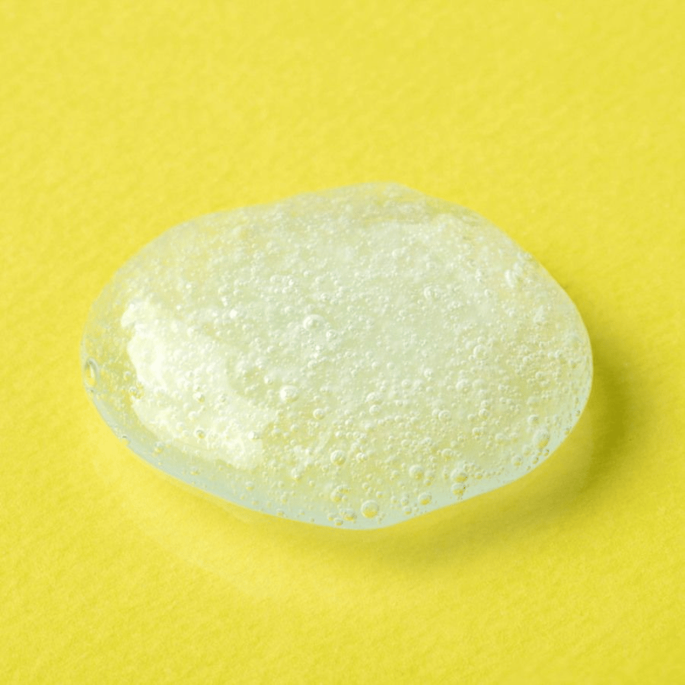 Prozorna gel tekstura iz COSRX Advanced Snail Mucin Gel Cleanser na rumenem ozadju – vlažilno čistilo za obraz s polžjim sekretom za mehko in uravnoteženo kožo.