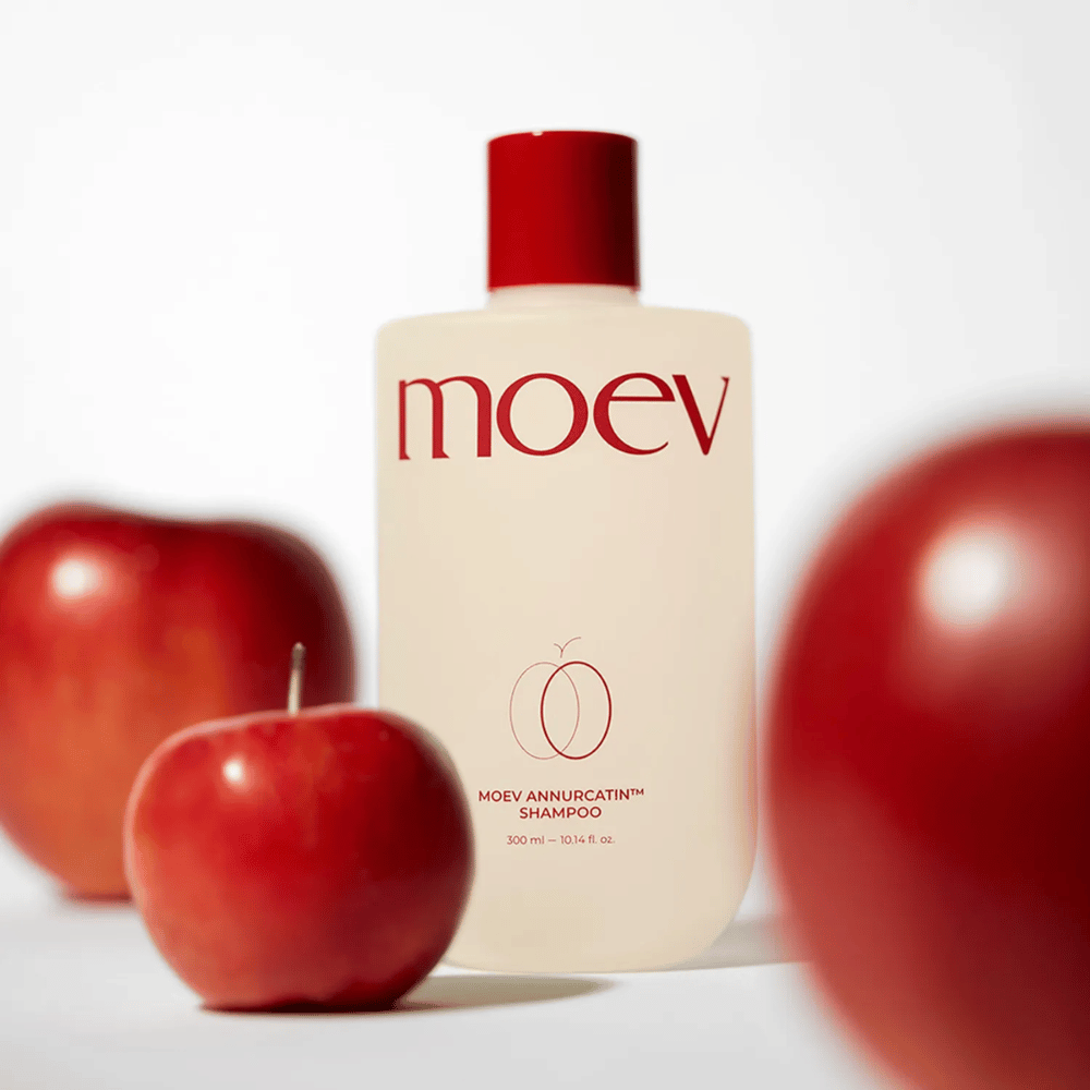 MOEV Annurcatin Shampoo postavljen med rdeča jabolka – navdihnjen z antioksidanti Annurca jabolka, ki dajejo močnejše, bolj zdrave in bolj sijoče lase.