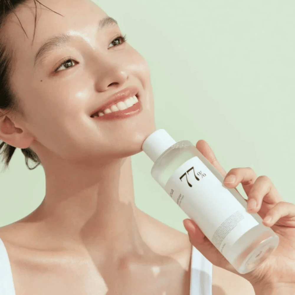 Ženska pomirja svojo občutljivo kožo s stekleničko Heartleaf 77% Soothing Toner od Anua, ki vsebuje ekstrakt listov kameleona.
