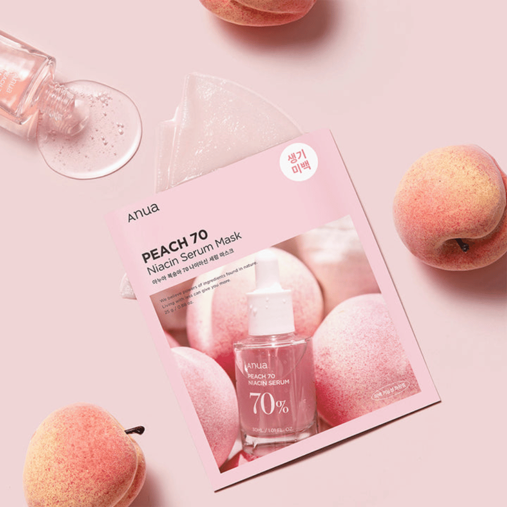 Slika Anua PEACH 70 Niacin Serum Mask, obdana z breskvami in stekleničko seruma. Slika ima mehko rožnato ozadje, ki dopolnjuje rožnato embalažo in poudarja izdelek ter sestavine.