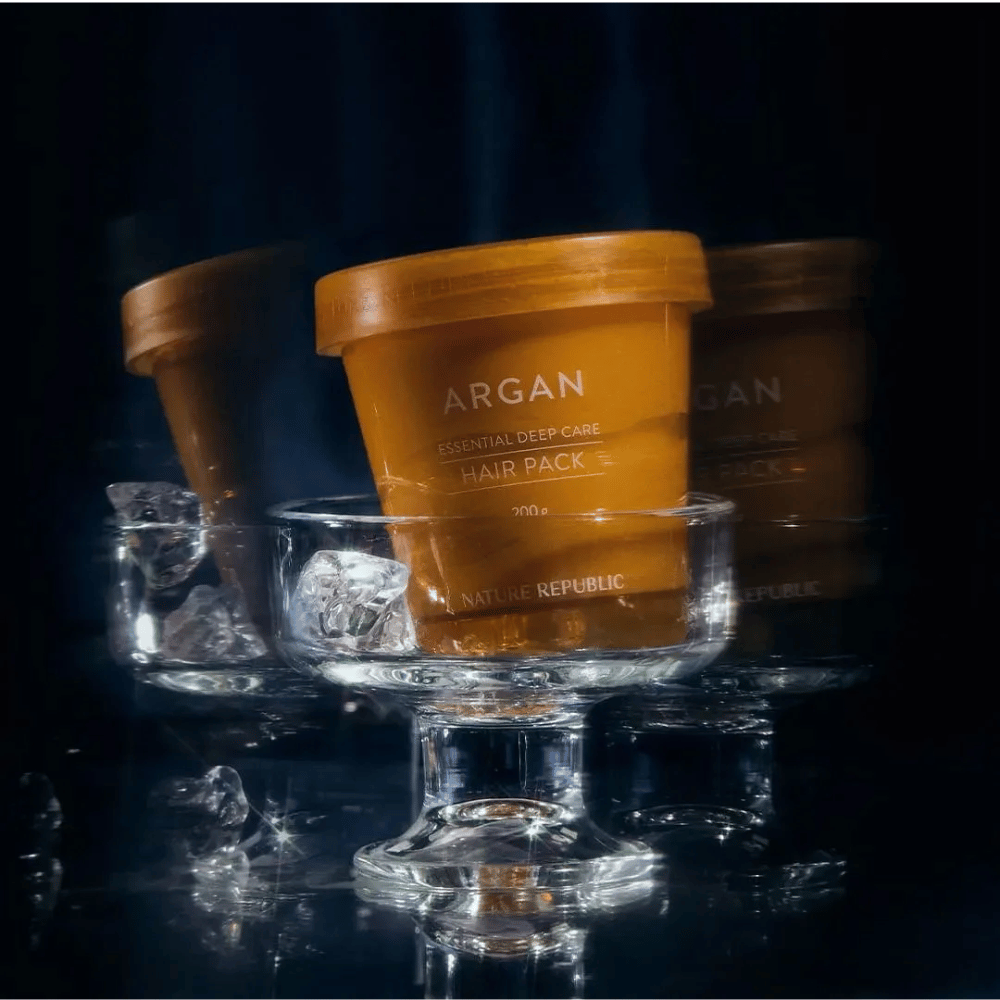 Nature Republic Argan Essential Moisture Repairing Hair Mask postavljena na steklen krožnik z ledenimi kockami – luksuzna in negovalna maska za lase.