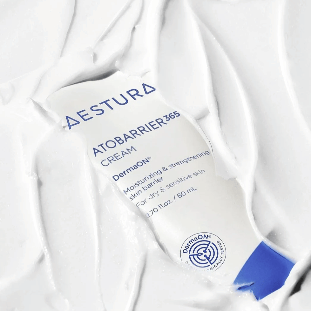 Aestura Atobarrier 365 Cream je popolna za suho in občutljivo kožo. Z DermaON™ tehnologijo ta krema vlaži in krepi kožno pregrado. Izdelek je prikazan tukaj v 80 ml tubi, delno prekrit z lastno kremasto teksturo, kar poudarja njegove bogate, vlažilne lastnosti.