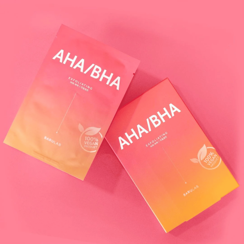 Dva izdelka BARULAB, eden v vrečki in eden v kartonski škatli, oba označena z "AHA/BHA" in "Exfoliating" na roza ozadju. Izdelki so označeni kot "100% Vegan Product".