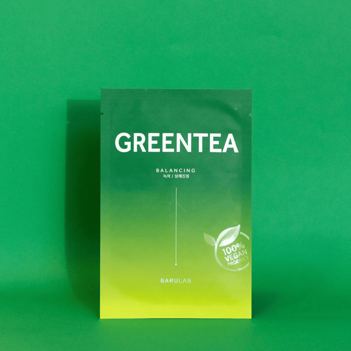 Embalaža od BARULAB za masko "GREENTEA Balancing", označena kot "100% Vegan Product". Barva embalaže prehaja iz temno zelene zgoraj v svetlejšo zeleno spodaj, na enotnem zelenem ozadju.