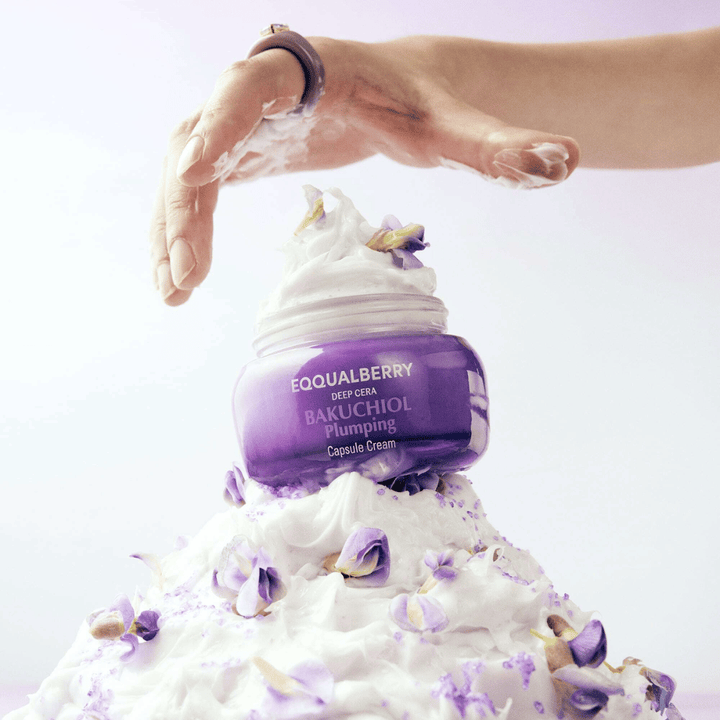 EQQUALBERRY Bakuchiol Plumping Capsule Cream postavljena na kup stepene kreme z cvetnimi listi – simbolizira vlago in nego.
