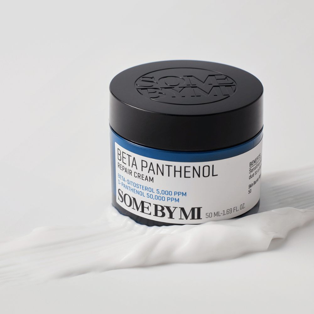 SOME BY MI Beta Panthenol Repair Cream v modri posodici, postavljen na teksturo kreme – pomirjujoča in vlažilna krema za kožo.