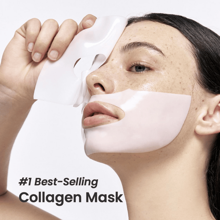 Slika prikazuje mlado žensko, ki nanaša Bio-Collagen Real Deep Mask iz Biodance, obrazno masko, ki je označena kot "#1 Best-Selling Collagen Mask". Maska je bela in pokriva njena lica in usta, kar poudarja njeno priljubljenost in učinkovitost za nego kože.