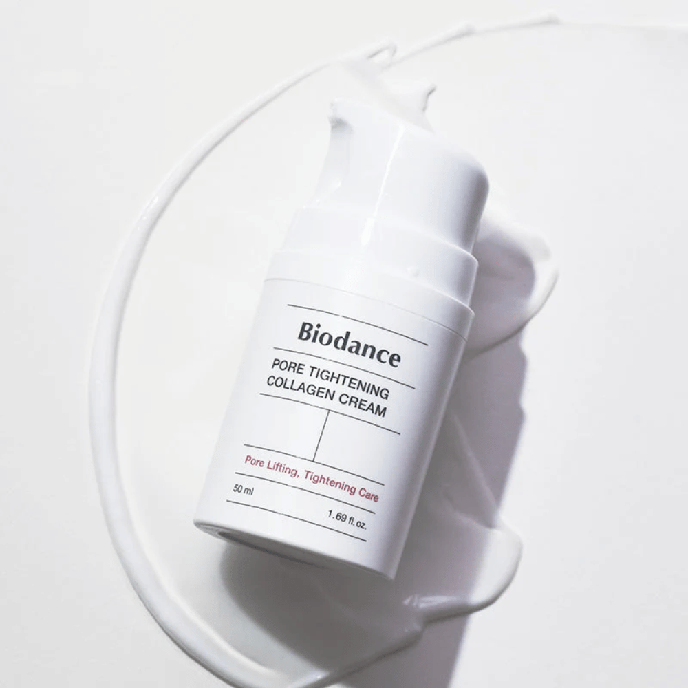 Biodance Pore Tightening Collagen Cream v beli steklenički s pumpico, ležeča na vrtincu bele kreme.