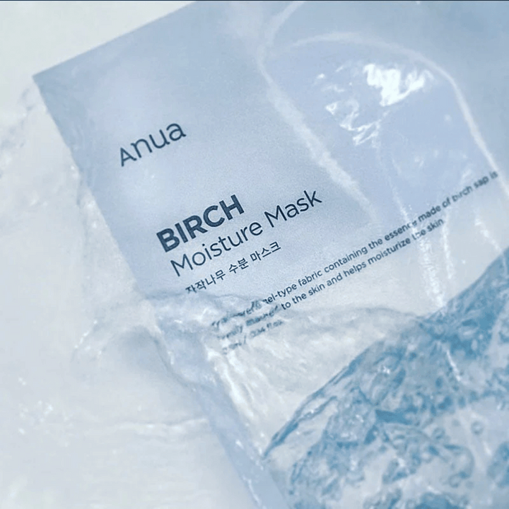 Slika prikazuje embalažo "Anua Birch Moisture Mask". Embalaža je v mehki modri barvi, besedilo pa je v angleščini in korejščini. Izdelek je opisan kot vlažilna obrazna maska iz brezovega soka, namenjena negi in vlaženju kože.