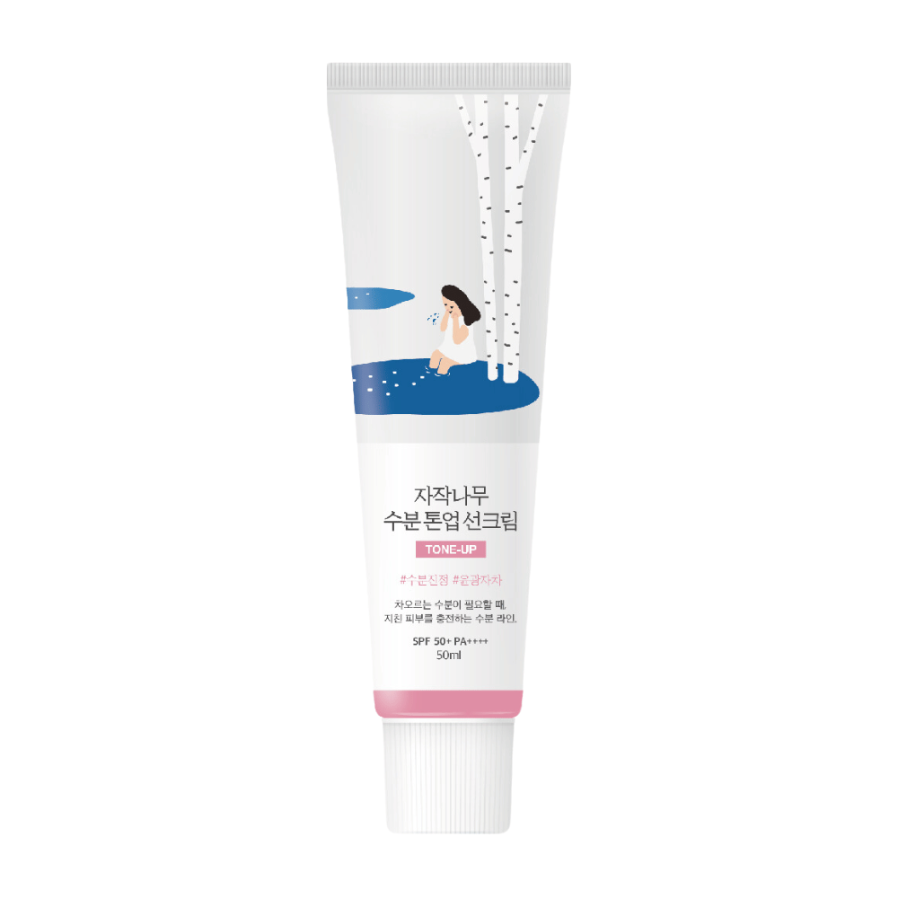 Bela tuba z Birch Juice Moisturizing Tone Up Sunscreen. Tuba ima ilustracijo ženske, ki sedi ob brezi poleg luže. Besedilo na tubi je v korejščini in navaja, da ima izdelek SPF 50+ PA++++ in vsebuje 50 ml.