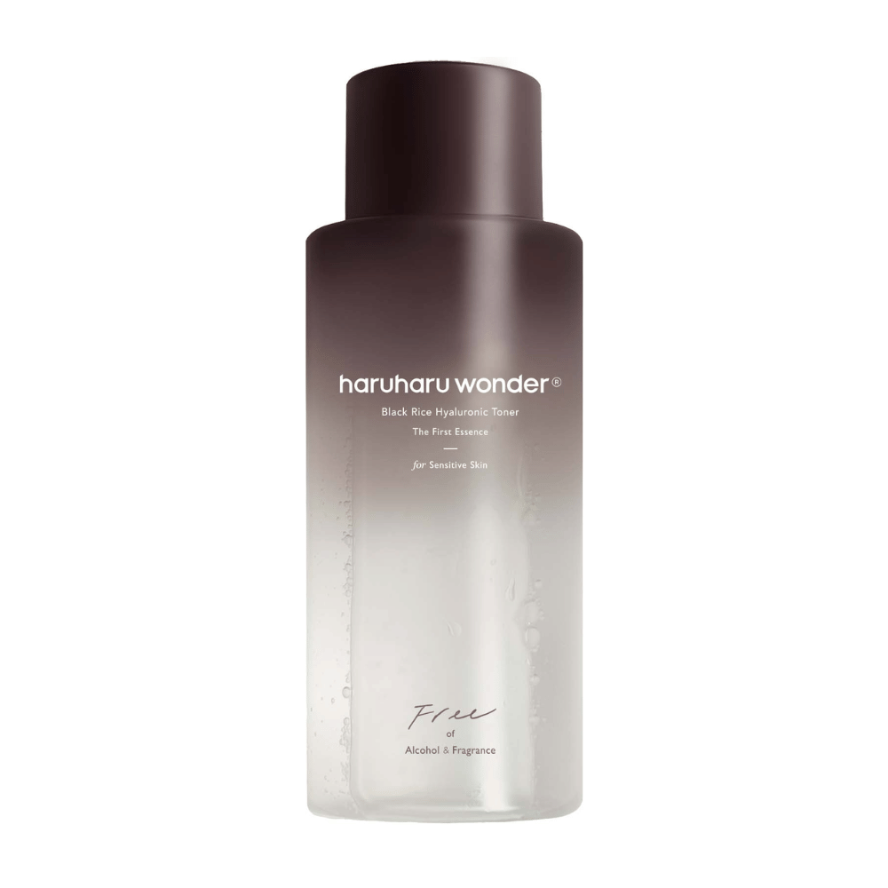 Steklenica haruharu wonder Black Rice Hyaluronic Toner The First Essence, z gradientom od temno rjave do prozorne in napisom "Brez alkohola in dišav", na beli podlagi.