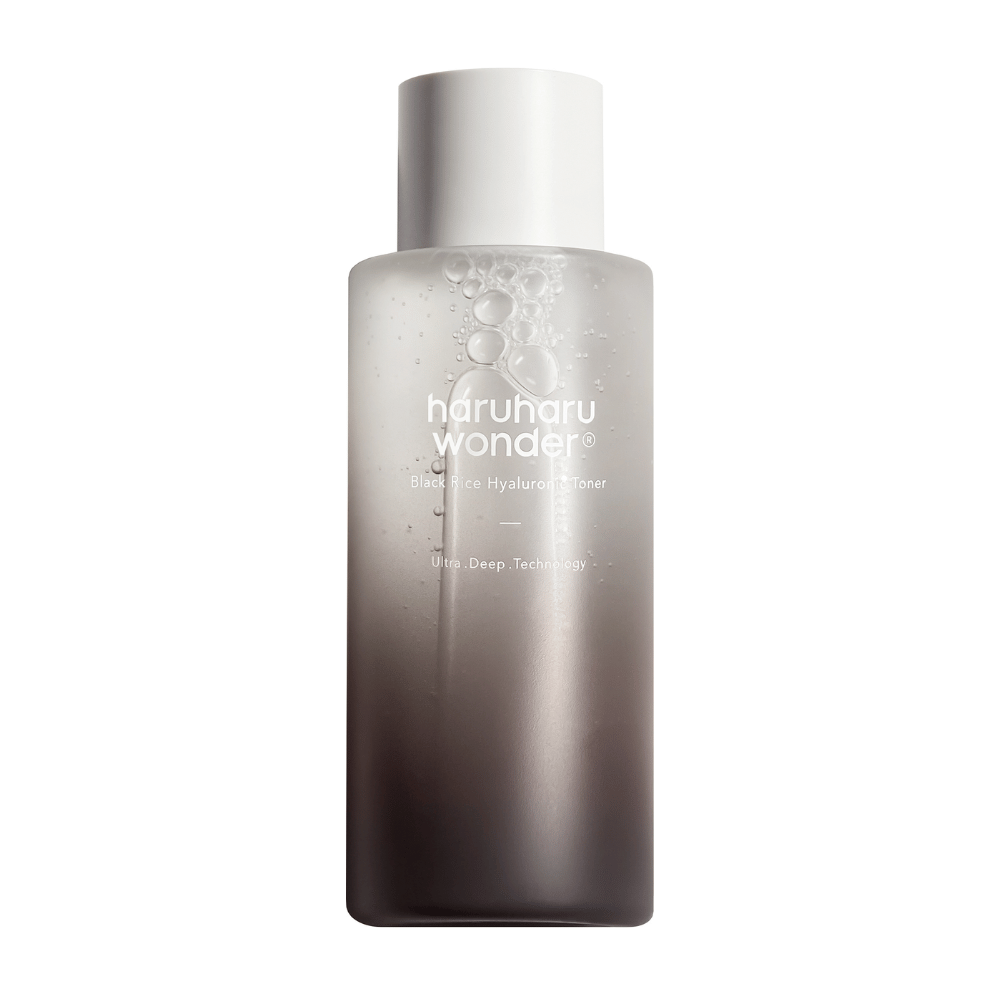 Steklenica haruharu wonder Black Rice Hyaluronic Toner z barvnim gradientom od sive do bele in kapljicami vode na površini, na beli podlagi.