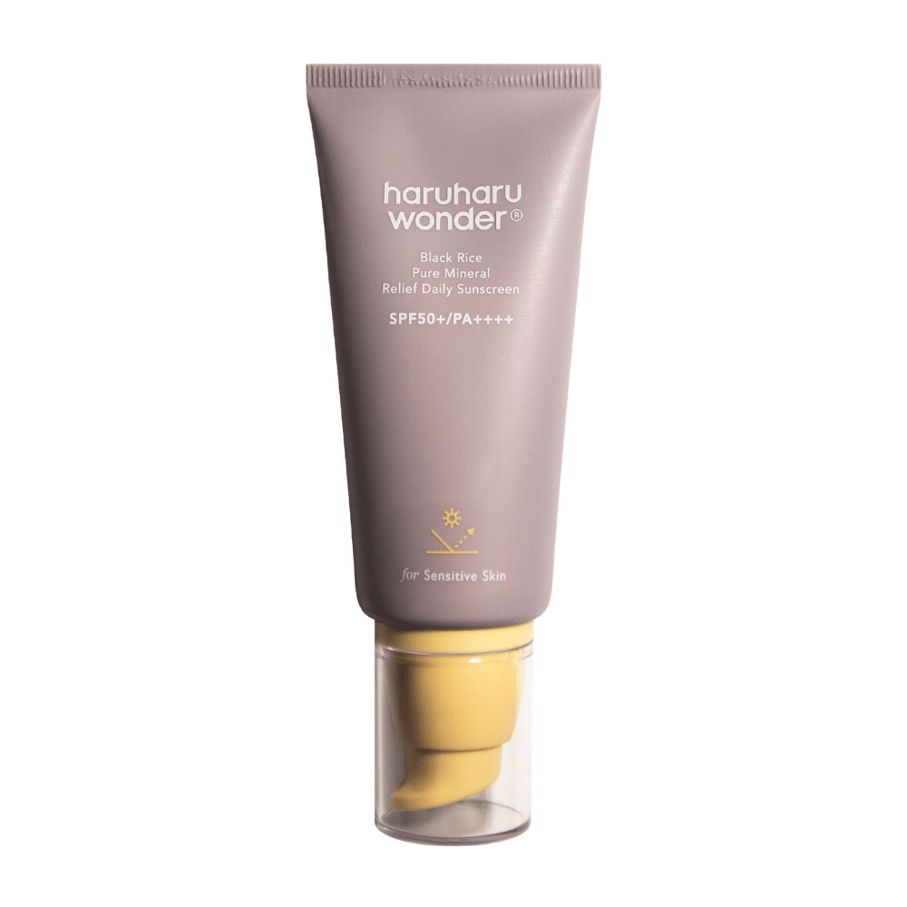 Vijolična tuba z Haruharu Wonder Black Rice Pure Mineral Relief Daily Sunscreen SPF 50+ PA++++. Tuba ima prozoren pokrovček in besedilo, ki opisuje visoko raven zaščite kreme za sončenje, posebej prilagojeno za občutljivo kožo.