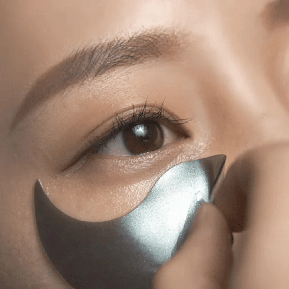 Podrobna slika, na kateri je črn hidrogelni eye patch nameščen pod očesom. Slika prikazuje tesno prileganje in hladilen občutek okoli predela oči.