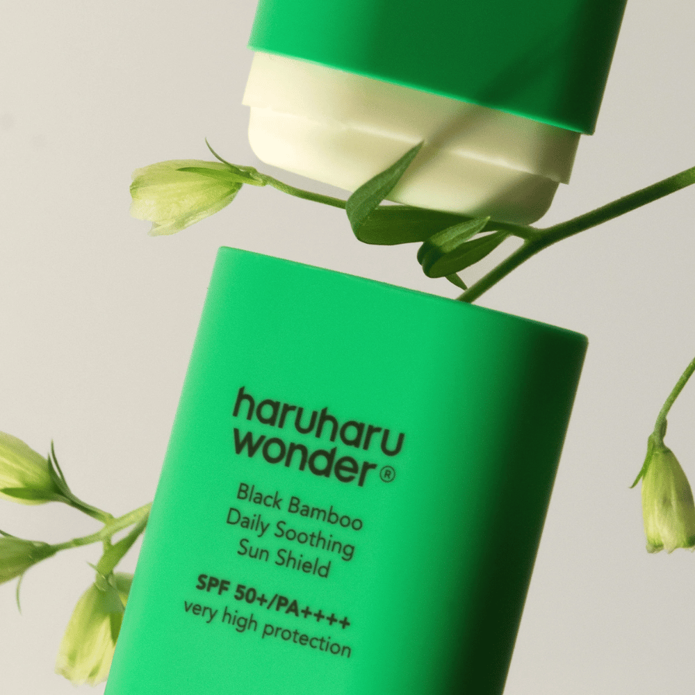 Približan posnetek Haruharu Wonder Black Bamboo Daily Soothing Sun Shield – zelenega zaščitnega stika s SPF 50+ PA++++, obdanega z zelenimi rastlinskimi detajli.