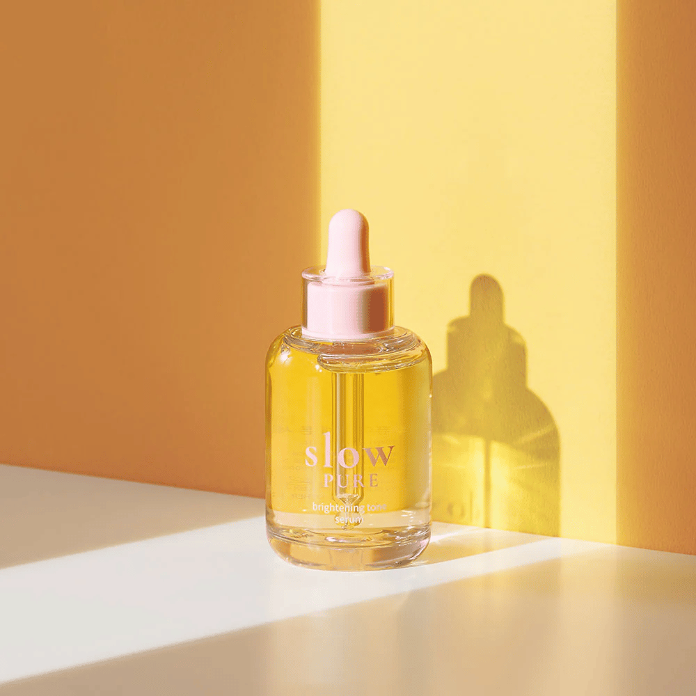 Slow Pure Brightening Tone Serum v sončni rumeni svetlobi, simbolizira sijaj in energijo za kožo.