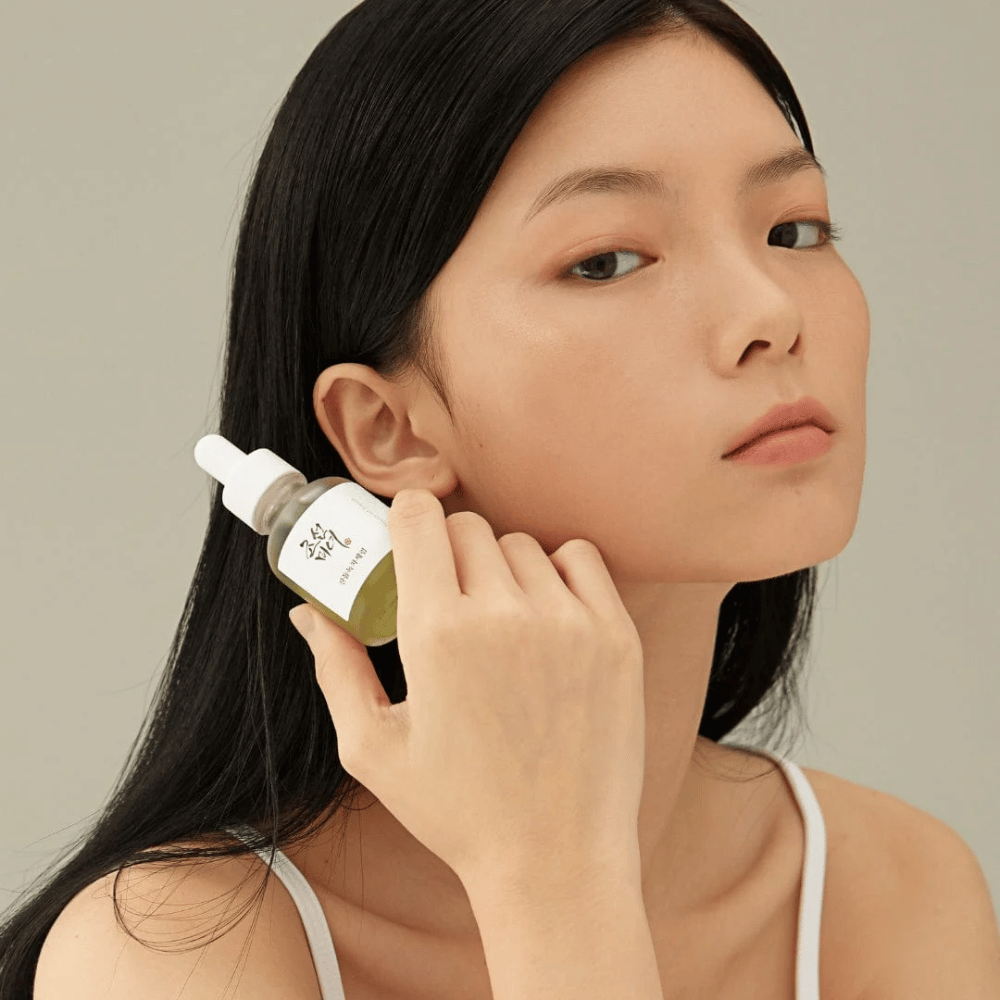 Model drži Beauty of Joseon Calming Serum pri licu – zeleni čaj in pantenol, ki krepita kožno pregrado.