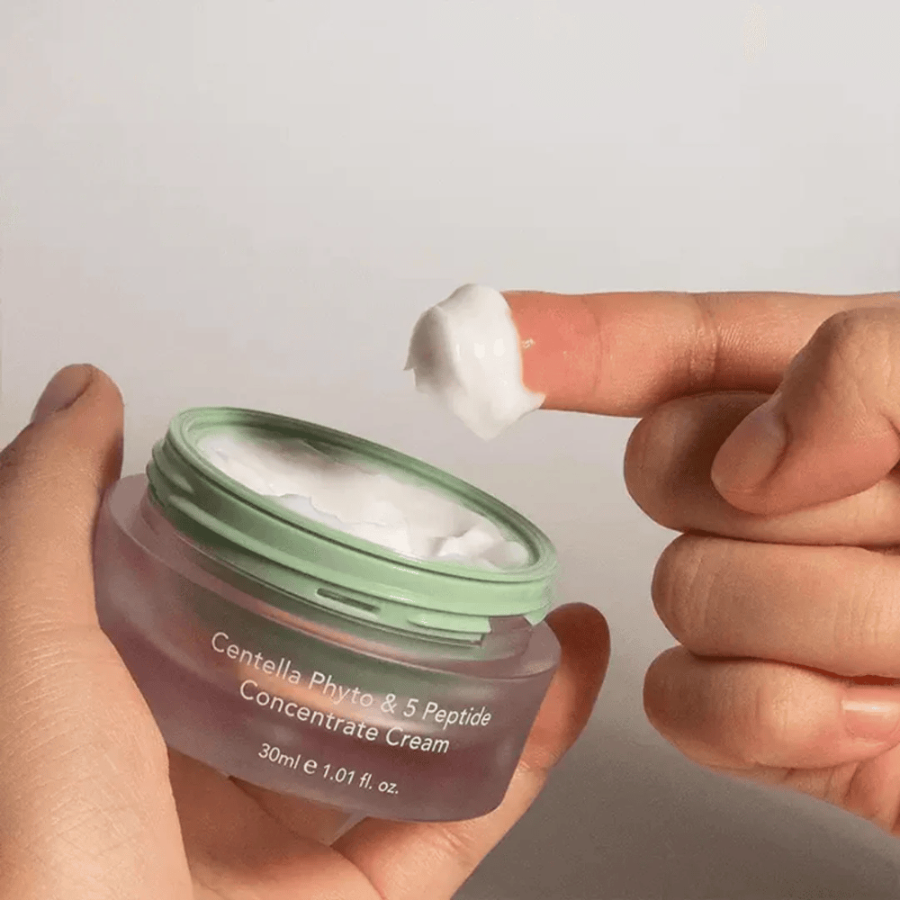 Roka, ki vzame klik Centella Phyto & 5 Peptide Concentrate Cream iz posode.
