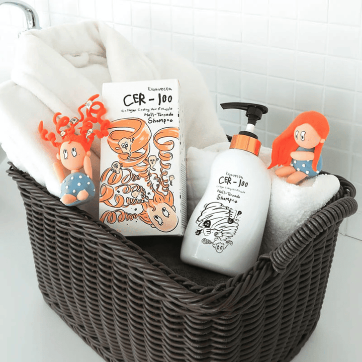 Predstavitvena slika z Elizavecca CER-100 Shampoo in embalažo izdelka, postavljenima v košaro skupaj z brisačami. Igrive figure iz oblikovanja embalaže poudarjajo edinstven in kreativen slog blagovne znamke.