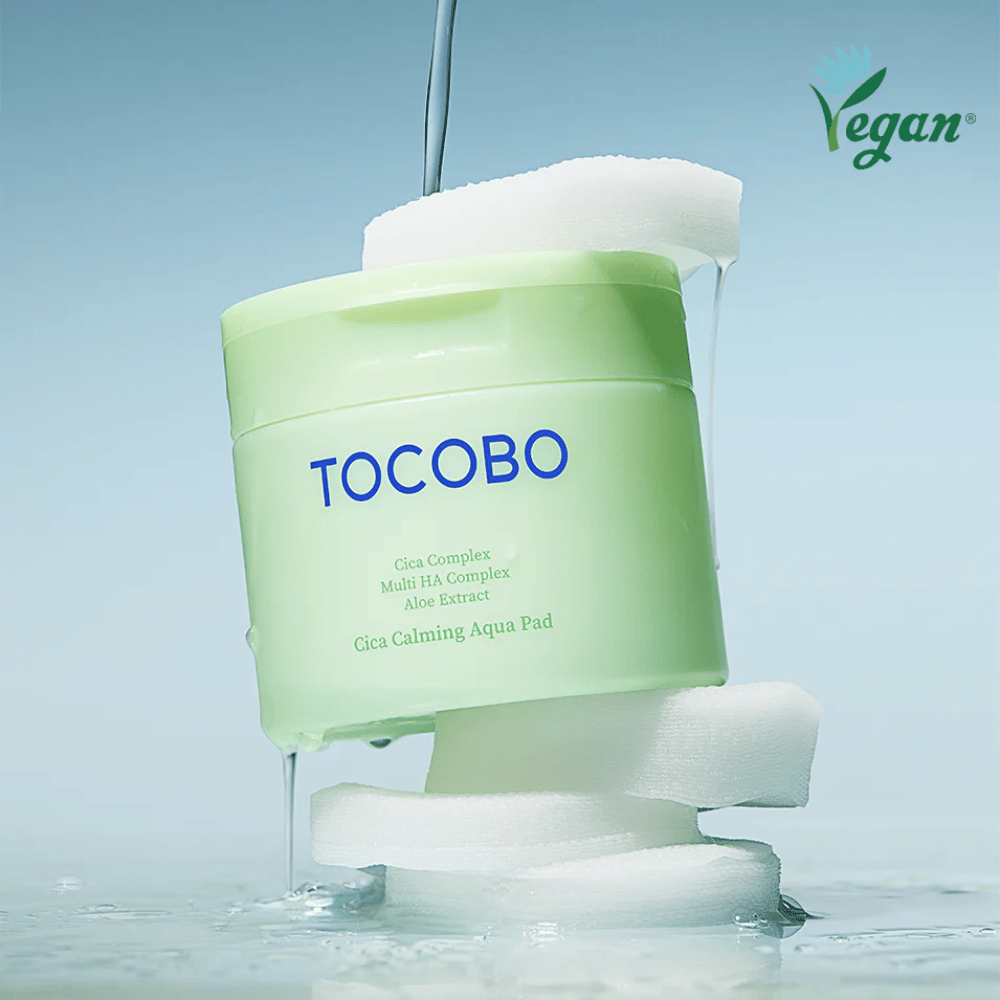 TOCOBO Cica Calming Aqua Pad, postavljen med toner pads z tekočo esenca. Veganski simbol poudarja vegansko formulacijo izdelka in koži prijazen profil.