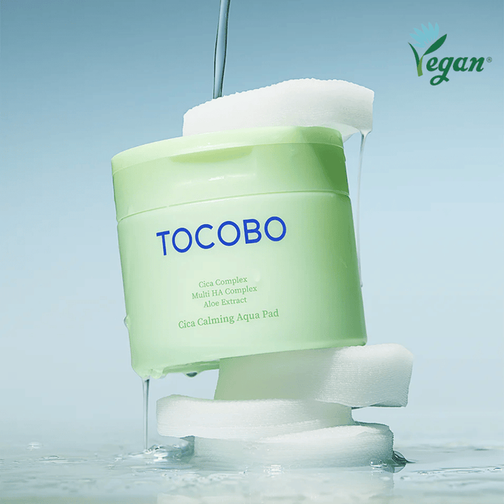TOCOBO Cica Calming Aqua Pad, postavljen med toner pads z tekočo esenca. Veganski simbol poudarja vegansko formulacijo izdelka in koži prijazen profil.