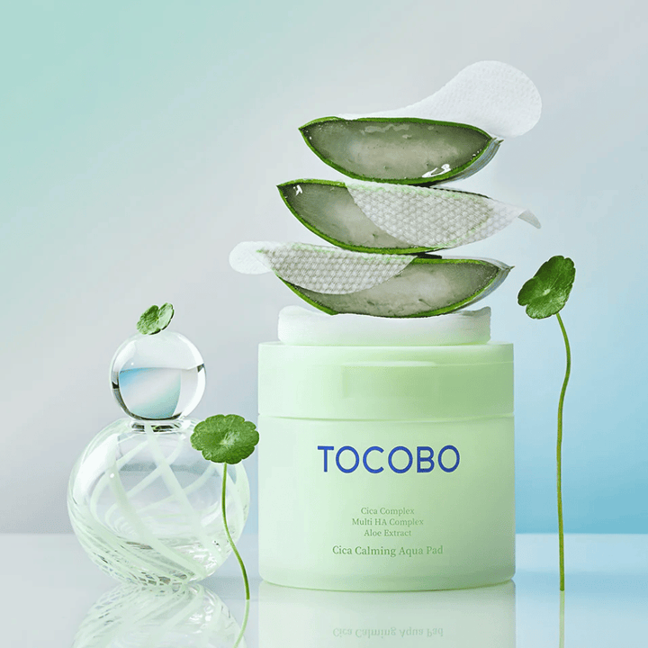 TOCOBO Cica Calming Aqua Pad je prikazan skupaj z toner pads, aloe vero in centello asiatico. Slika izpostavlja vlažilne in pomirjujoče sestavine izdelka.