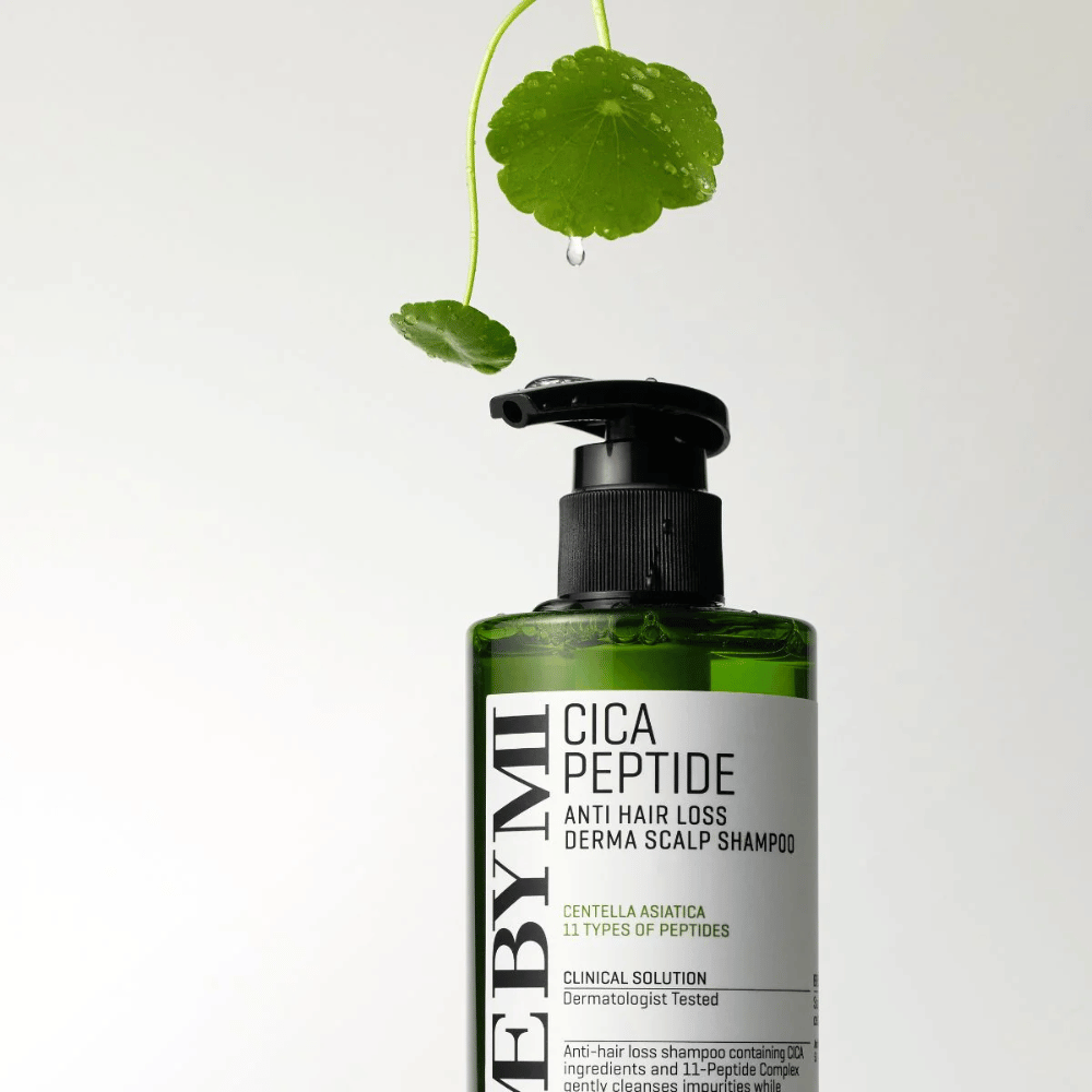 Steklenica SOME BY MI Cica Peptide Anti Hair Loss Derma Scalp Shampoo v zeleni barvi s črno črpalko in belo etiketo, obdana s centela listi in kapljico vode.