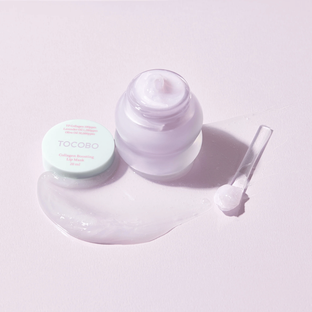 Odprta posoda TOCOBO Collagen Boosting Lip Mask s spatulo in razprto vijolično kremo na svetlo vijoličnem ozadju.