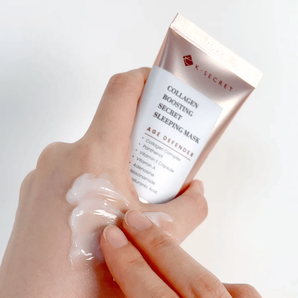 Roka drži Collagen Boosting Secret Sleeping Mask, medtem ko druga nanaša velikodušno količino kreme na zgornji del roke – prikazuje konsistenco in nanos izdelka.