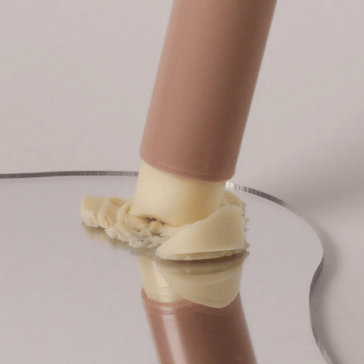 Povečana slika multi balm stika, ki se pritisne na površino s kremasto konsistenco.