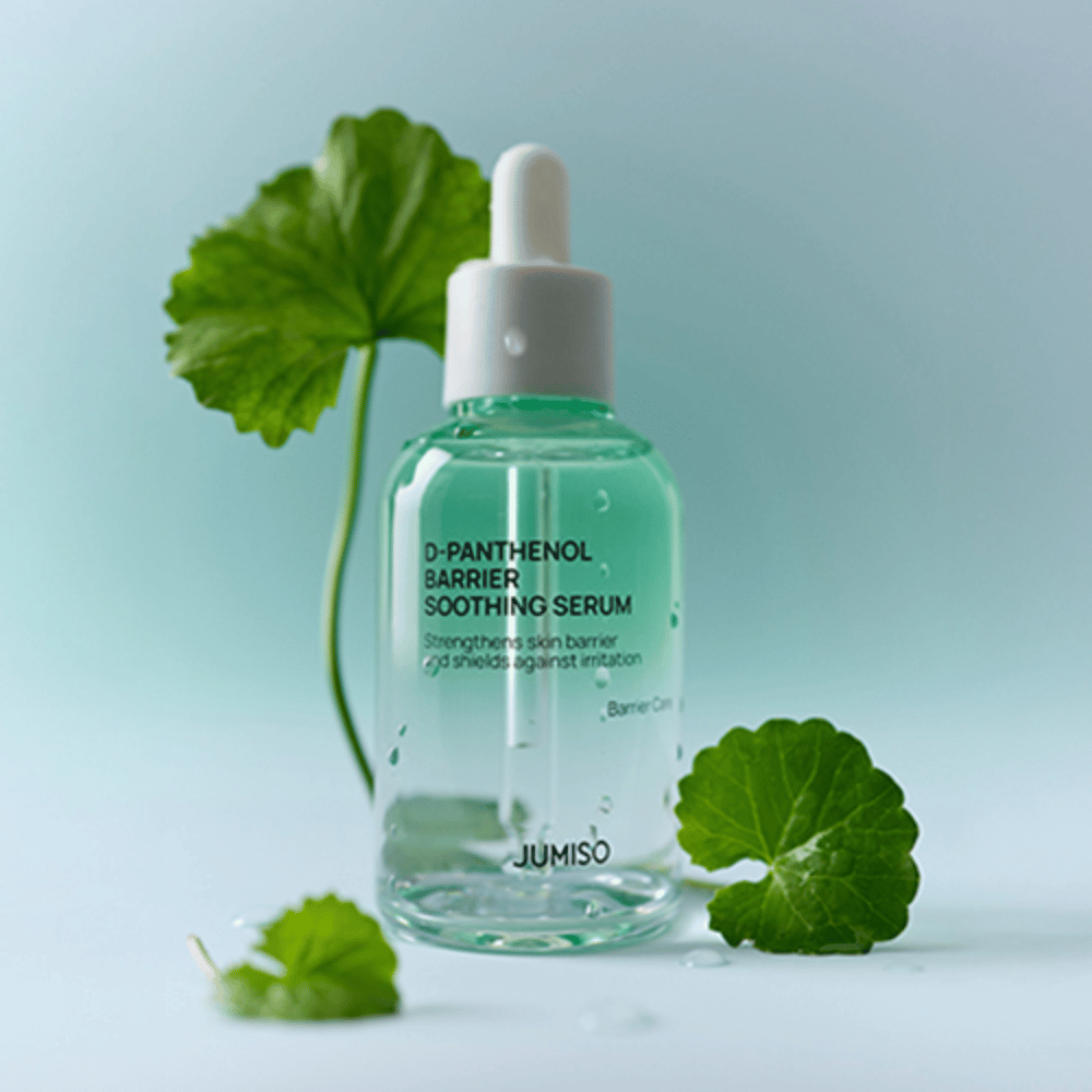 Jumiso D-Panthenol Barrier Soothing Serum v prozorni steklenici s pipeto, postavljen z zelenimi listi v ozadju.