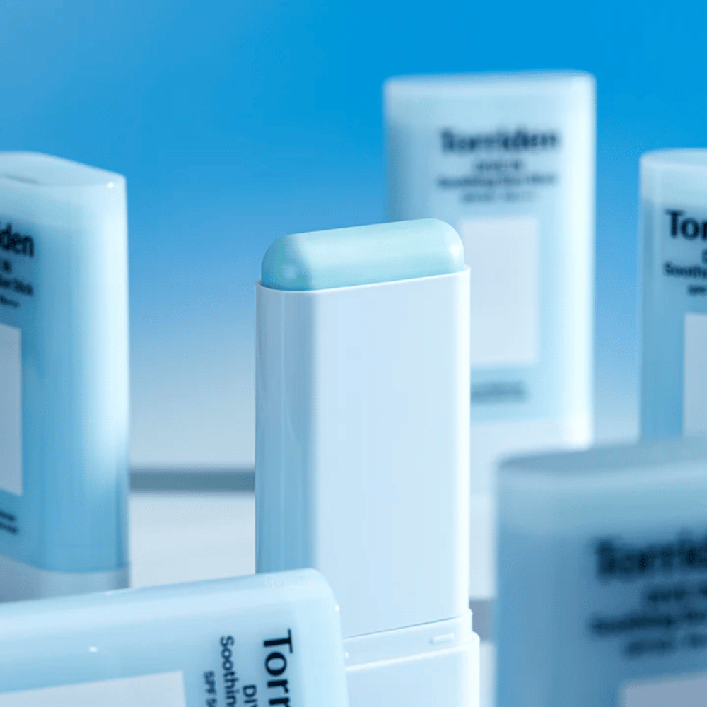 Bližnji posnetek Torriden DIVE IN Soothing Sun Stick, ki prikazuje mehko formulo zaščite pred soncem v obliki stika z več izdelki v ozadju.