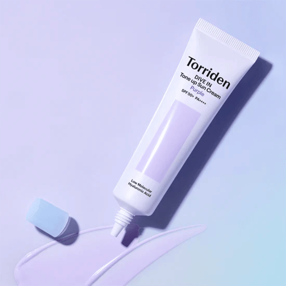 Odprta tuba Torriden DIVE IN Tone Up Sun Cream Purple z vijolično obarvano teksturo sončne kreme, ki prikazuje barvno korektivno formulo izdelka.
