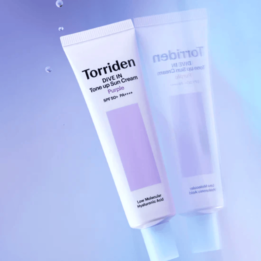 Torriden DIVE IN Tone Up Sun Cream Purple SPF50+ PA++++ fotografirana na mehkem vijoličnem ozadju, ki poudarja svetlobo odsevajoč dizajn izdelka.