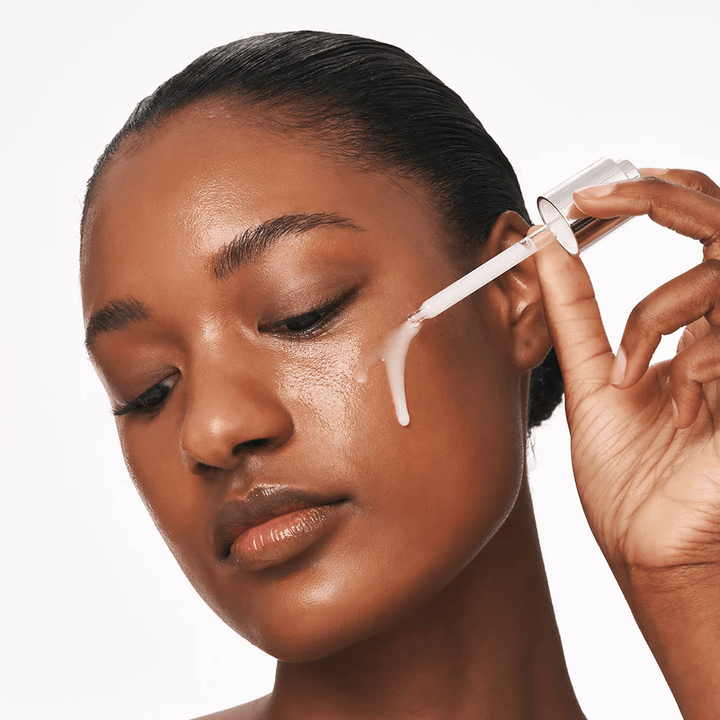 Oseba nanaša Deep Collagen Power Boosting Cream in Serum na lice s pipeto. Serum daje čvrstejšo, navlaženo kožo z leskom.