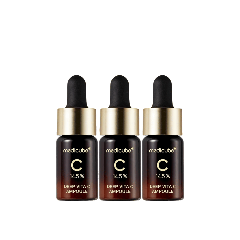 Tri stekleničke Medicube Deep Vita C Ampoule, s 14,5 % vitamina C, razporejene v vrsti. Stekleničke imajo eleganten dizajn s temno rjavo osnovo in zlatim pokrovčkom. Popolno za svetlejši ten kože in enakomernejšo teksturo kože.