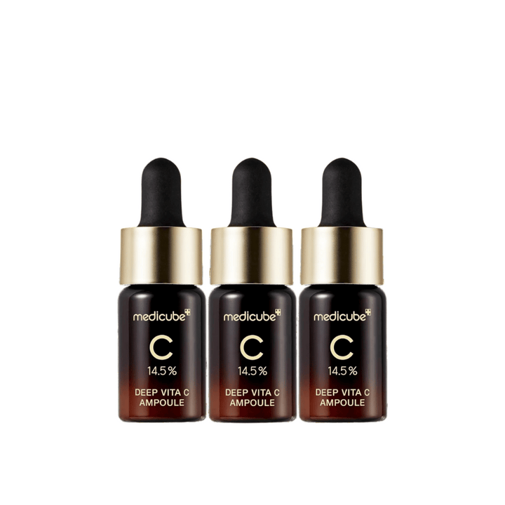 Tri stekleničke Medicube Deep Vita C Ampoule, s 14,5 % vitamina C, razporejene v vrsti. Stekleničke imajo eleganten dizajn s temno rjavo osnovo in zlatim pokrovčkom. Popolno za svetlejši ten kože in enakomernejšo teksturo kože.