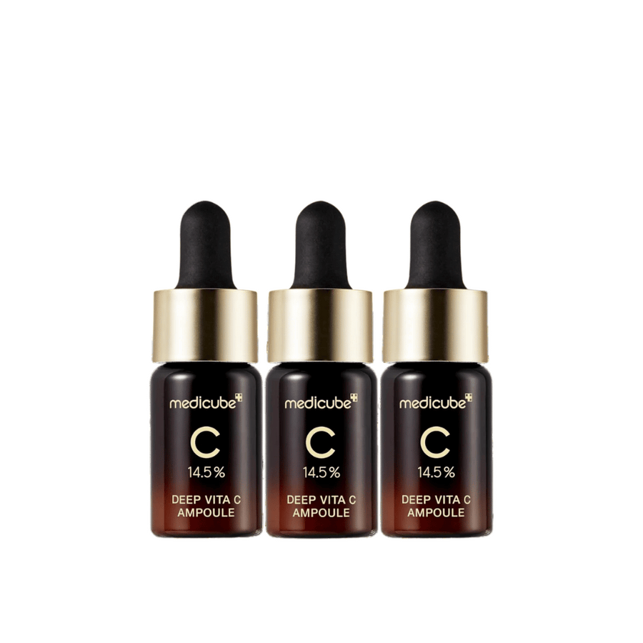 Tri stekleničke Medicube Deep Vita C Ampoule, s 14,5 % vitamina C, razporejene v vrsti. Stekleničke imajo eleganten dizajn s temno rjavo osnovo in zlatim pokrovčkom. Popolno za svetlejši ten kože in enakomernejšo teksturo kože.