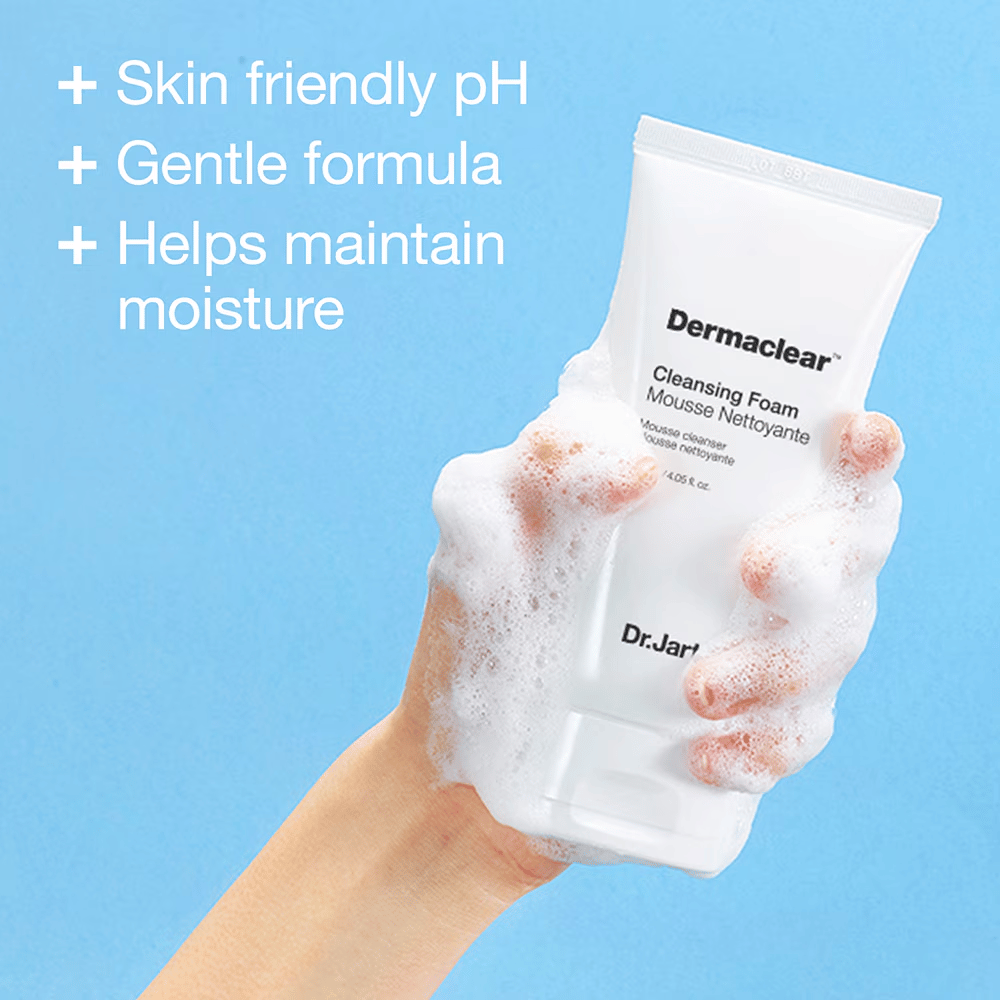 Roka prekrita z milnico drži Dr.Jart+ Dermaclear Cleansing Foam proti modremu ozadju, z besedilom, ki poudarja koži prijazen pH, blago formulo in vlažilne lastnosti.