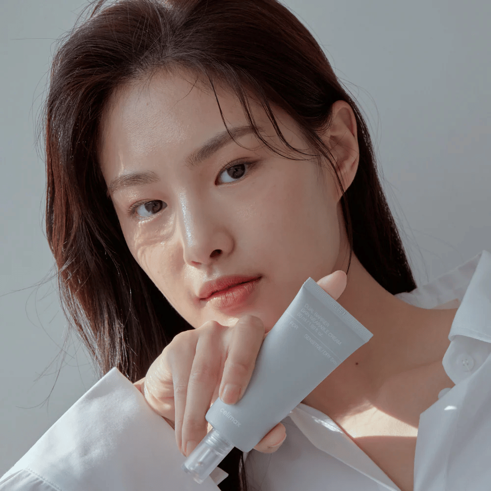 Model, ki drži Celimax Dual Barrier Skin Wearable Cream, pomirjujoča in krema za obraz, ki krepi bariero, za občutljivo in suho kožo.