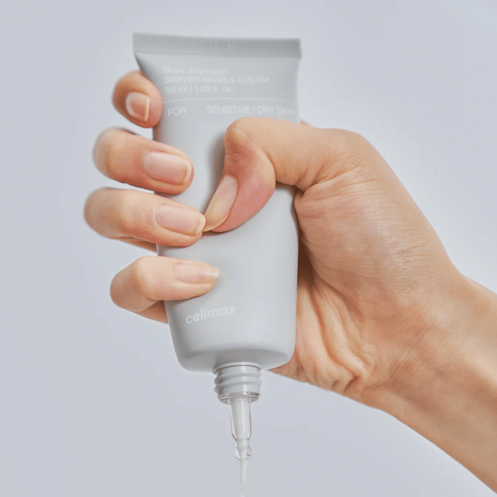 Roka, ki nanaša Celimax Dual Barrier Skin Wearable Cream, krema za obraz, ki krepi bariero, za občutljivo in suho kožo, ki zagotavlja dolgotrajno vlaženje in ščiti kožno bariero.