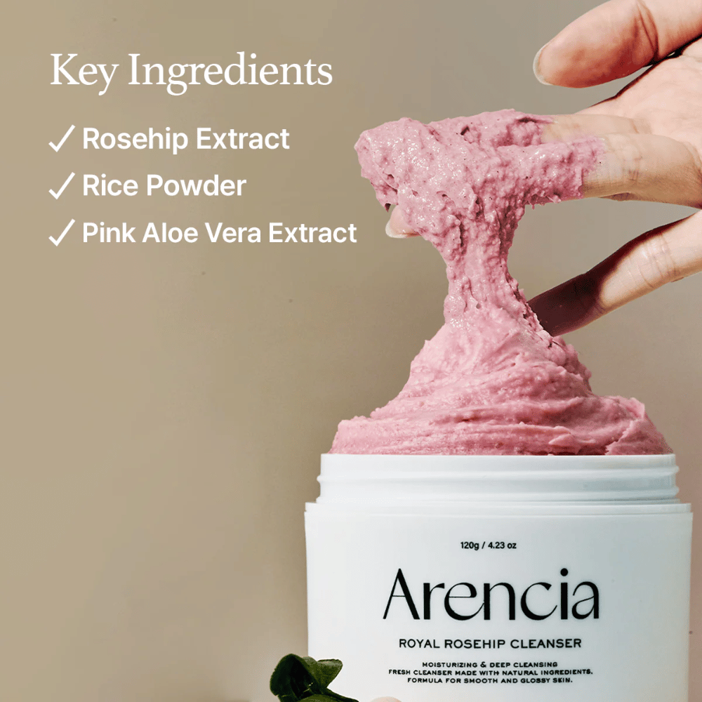Roka dviguje roza, puhasto čistilno teksturo iz lončka Arencia Royal Rosehip Cleanser, z seznamom sestavin na levi: izvleček šipka, rižev prah in izvleček roza aloe vere.